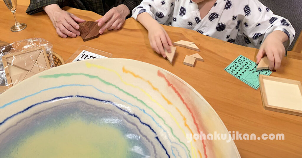テーブルで木製パズルを並べる、大人と子どもの手元